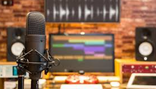 Một người đang hát trong phòng thu âm, phía sau là micro và tai nghe chuyên nghiệp, ánh sáng dịu nhẹ tạo cảm giác ấm áp.