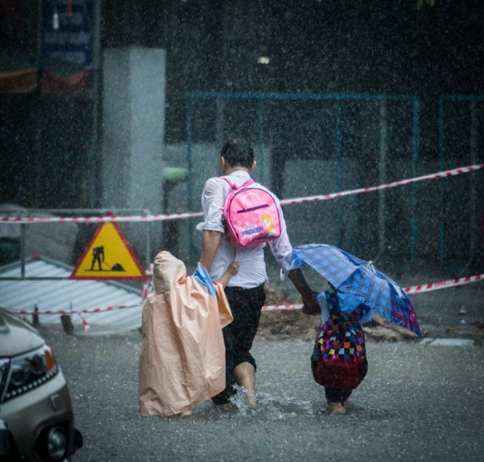 Hình ảnh cha mẹ nắm tay con đi qua cơn mưa, biểu tượng cho sự che chở và yêu thương vô điều kiện.
