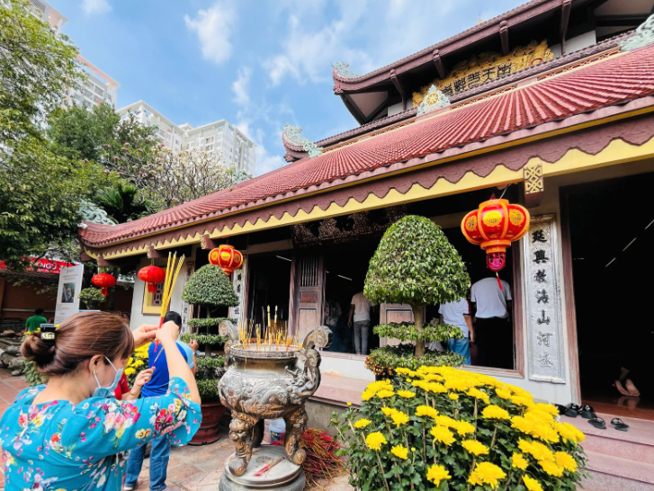 Hình ảnh người đi lễ trong khung cảnh chùa linh thiêng buổi sớm, ánh nắng nhẹ chiếu qua khói hương nghi ngút