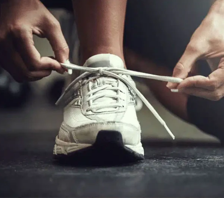 Một người đang buộc dây giày ba ta trên con đường mòn – biểu trưng cho sự chuẩn bị và quyết tâm tiến bước