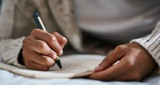 Bức ảnh tổng hợp người đang ngồi viết nhật ký giấc mơ, phía sau là ánh sáng vàng nhẹ – biểu tượng của tài lộc và hi vọng.