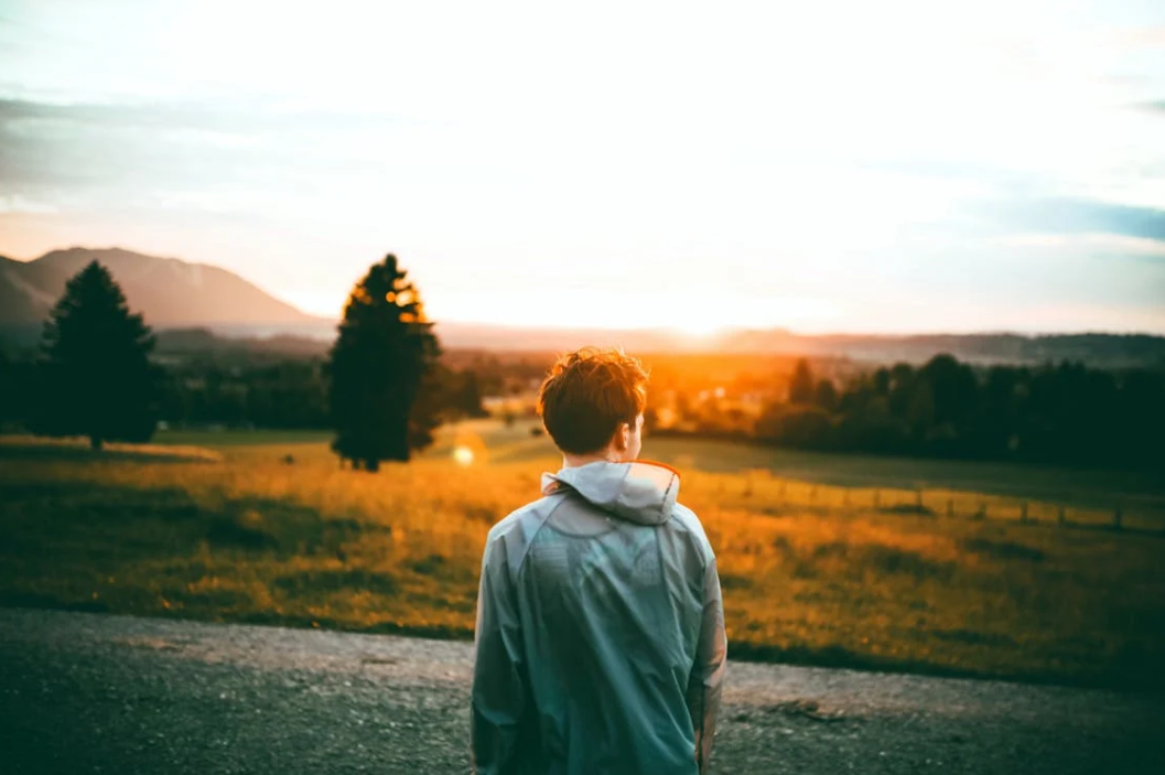 Ảnh chụp người đang đứng giữa ngã tư đường, phía trước là ánh sáng mặt trời – biểu trưng cho sự tự do và tái sinh.