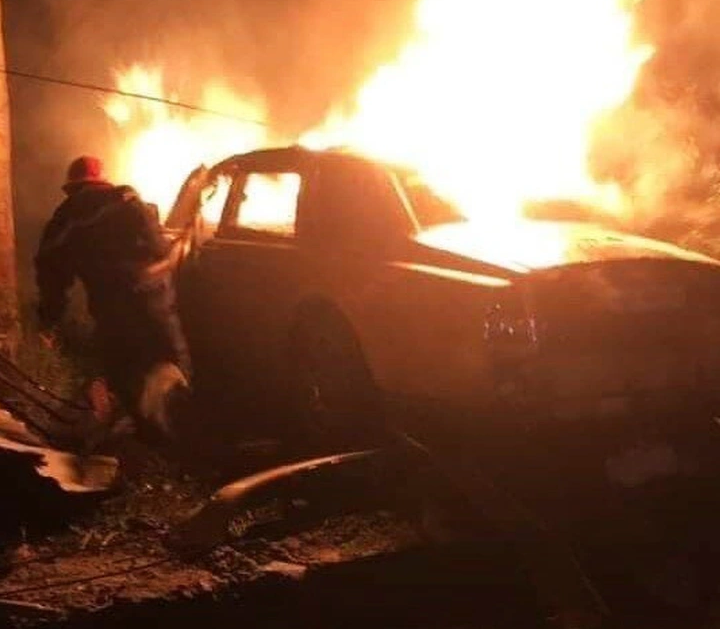 Một chiếc ô tô đang cháy trong màn đêm – tạo cảm giác huyền bí, khói và lửa bốc cao.