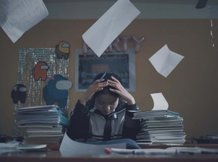 Một chiếc bàn học đầy giấy tờ, tượng trưng cho áp lực thi cử và tâm trạng căng thẳng.